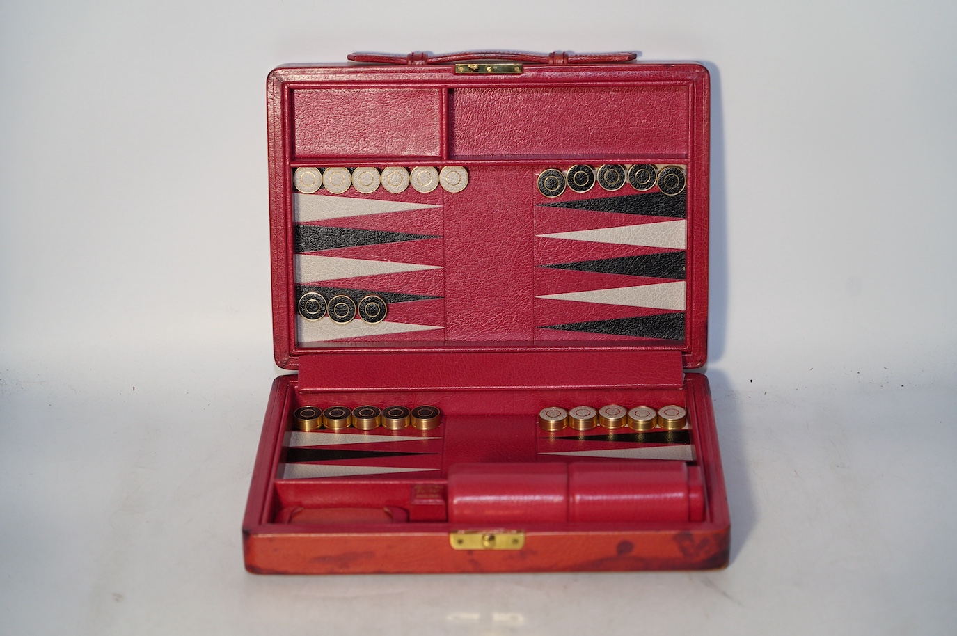 A Geoffrey Parker red leather backgammon set and a black leatherette wrist watch case